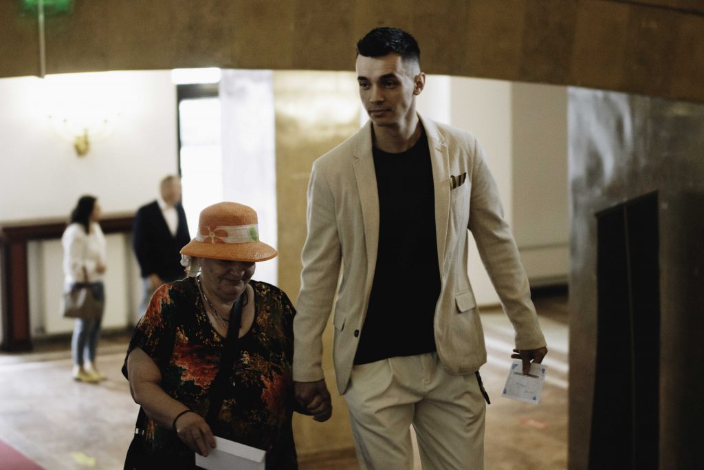 graduate helping his sibling up the stairs of sica alexandrescu theater at the american hotel academy graduation ceremony 2022