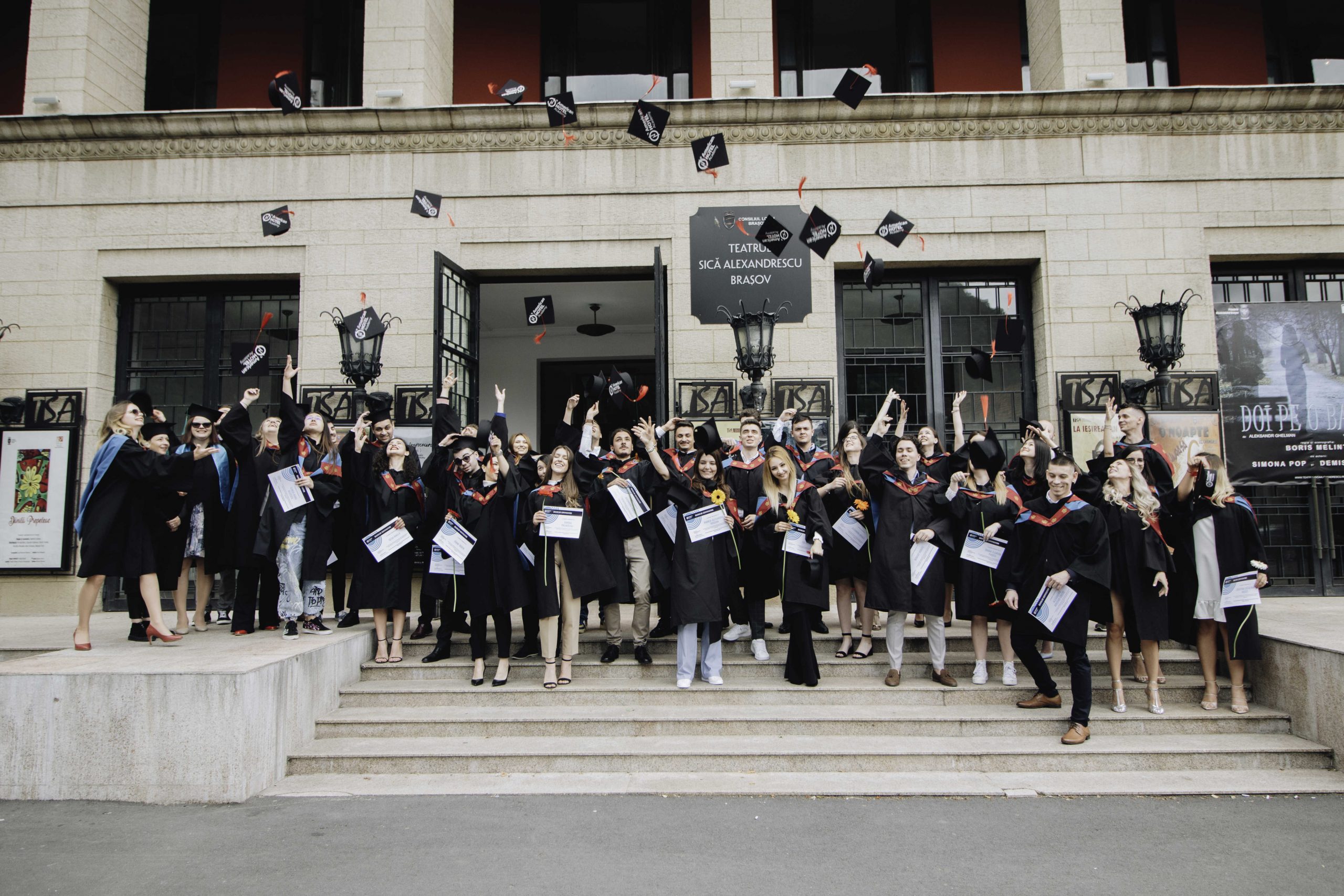 students throw their caps in the air to celebrate their graduation at the american hotel academy graduation ceremony 2022